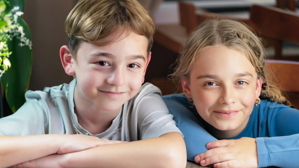 Kinder stärken, Familien glücklich, Welt friedlich - Ein Weg zum Erfolg Porträt von zwei starken Kindern, die in die Kamera lächeln